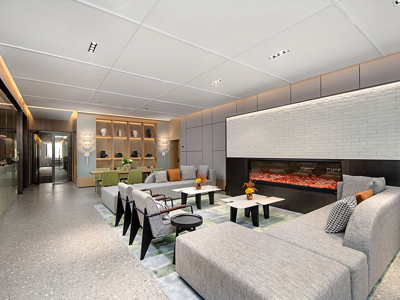 Una sala de estar moderna con chimenea, zona de estar y cocina al fondo.