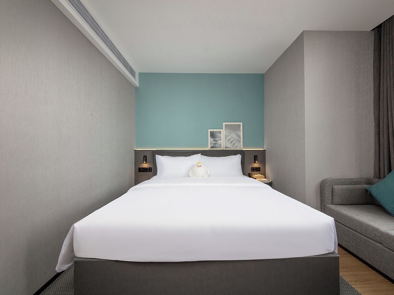 A hotel room with a bed, a sofa, and a nightstand.