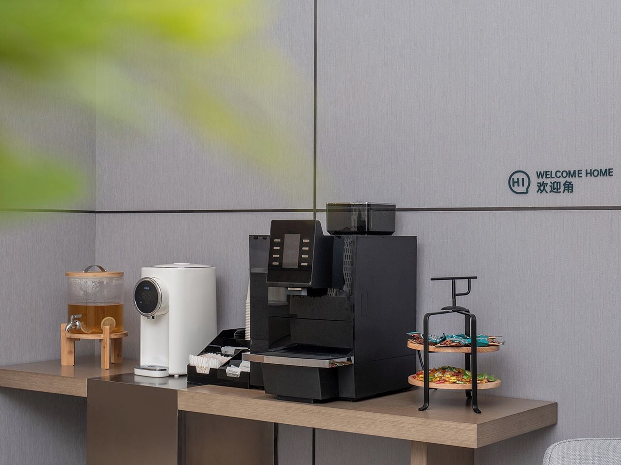 A coffee machine, a tea dispenser, and a fruit display on a counter.