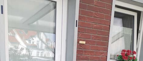 Ein Wohngebäude mit einer weißen Tür und einem Fenster mit einem Blumentopf.
