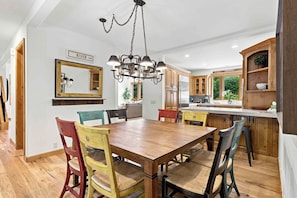 A modern kitchen with a central island, wooden cabinets, and a chandelier. - Spacious Warm Springs Home | Hot Tub + Bunk Room (Ketchum)