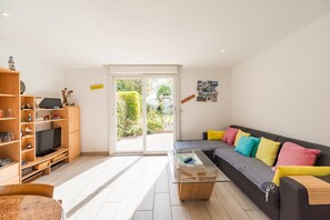 A modern living room with a sofa, coffee table, and a TV on a wooden shelf. - 3-bedroom house in Saint-Brieuc, comfort and quiet (Saint-Brieuc)