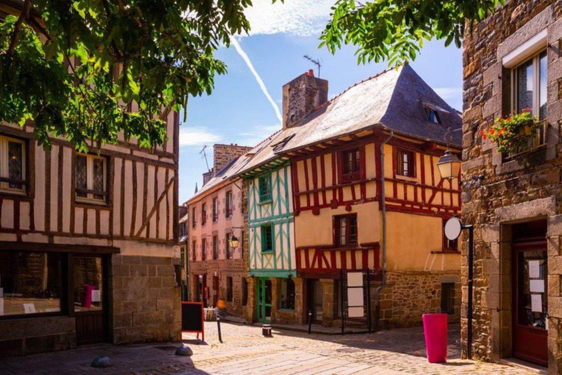 Une rue étroite bordée de bâtiments traditionnels à colombages, avec un pavé de pierres et un ciel dégagé.