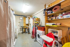 A laundry room with a washing machine, drying rack, and shelves stocked with cleaning supplies. - 3-bedroom house in Saint-Brieuc, comfort and quiet (Saint-Brieuc)
