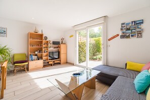 Ein modernes Wohnzimmer mit einer Couch, einem Glastisch, einem Fernseher und einem Bücherregal.