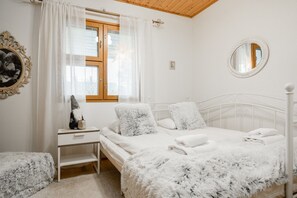 Ein Schlafzimmer mit einem Bett, einem Nachttisch, einem Spiegel und einem Fenster mit Vorhängen.