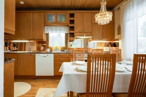 Eine moderne Küche mit Holzausstattung, einem Essbereich mit Tisch für vier Personen und einer Kandelaber.
