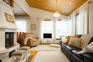 Ein Wohnzimmer mit Kamin, Ledersofa und Fernseher.