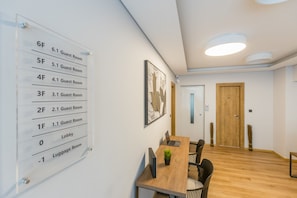 Eine Hotellobby mit einem gut sichtbaren Grundriss an der Wand, einem Holzbüroempfang und einer modernen Deckenleuchte.