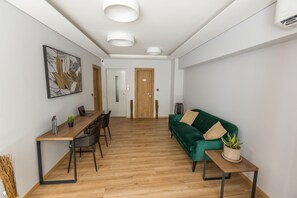 Un salon moderne avec une table à manger en bois, un canapé vert et une plante en pot.