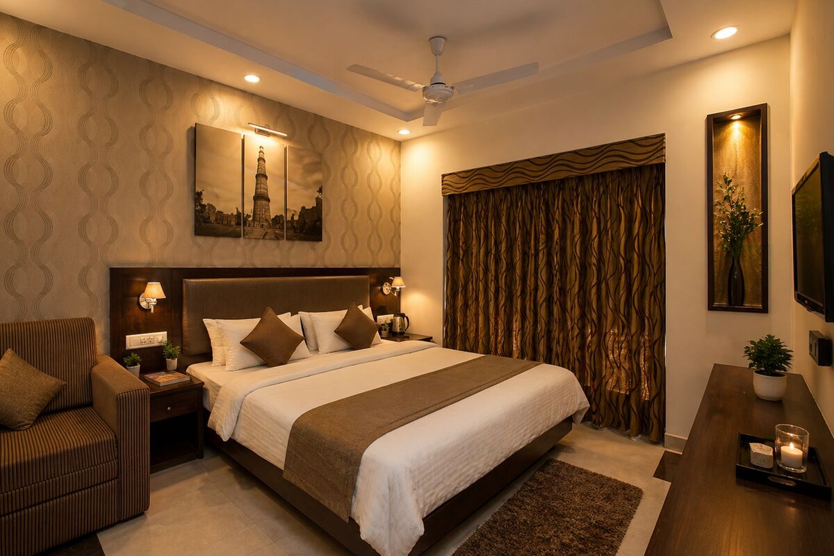 A hotel room with a large bed, a sofa, a flat-screen TV, and a ceiling fan.