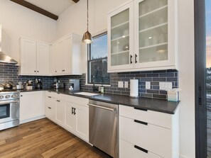 A modern kitchen with white cabinetry, a stainless steel dishwasher, and a black countertop. - New ! Big Sky Basin Home with Hot Tub, Game Room & Mountain Views (Big Sky)
