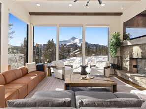 Ein modernes Wohnzimmer mit einem großen Fenster mit Blick auf eine verschneite Berglandschaft.