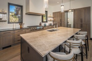 Een moderne keuken met een groot eiland, barkrukken en houten kastjes.