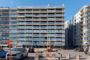 Ein mehrstöckiges Gebäude mit modernem architektonischen Design, das eine Reihe von Balkonen und große Fenster aufweist.