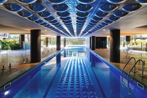 A long indoor swimming pool with a modern design, surrounded by glass walls and supported by large pillars. - North Edit - Port Melbourne Beachside (Port Melbourne)