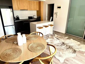 A modern kitchen with a refrigerator, stove, and bar stools. - North Edit - Port Melbourne Beachside (Port Melbourne)