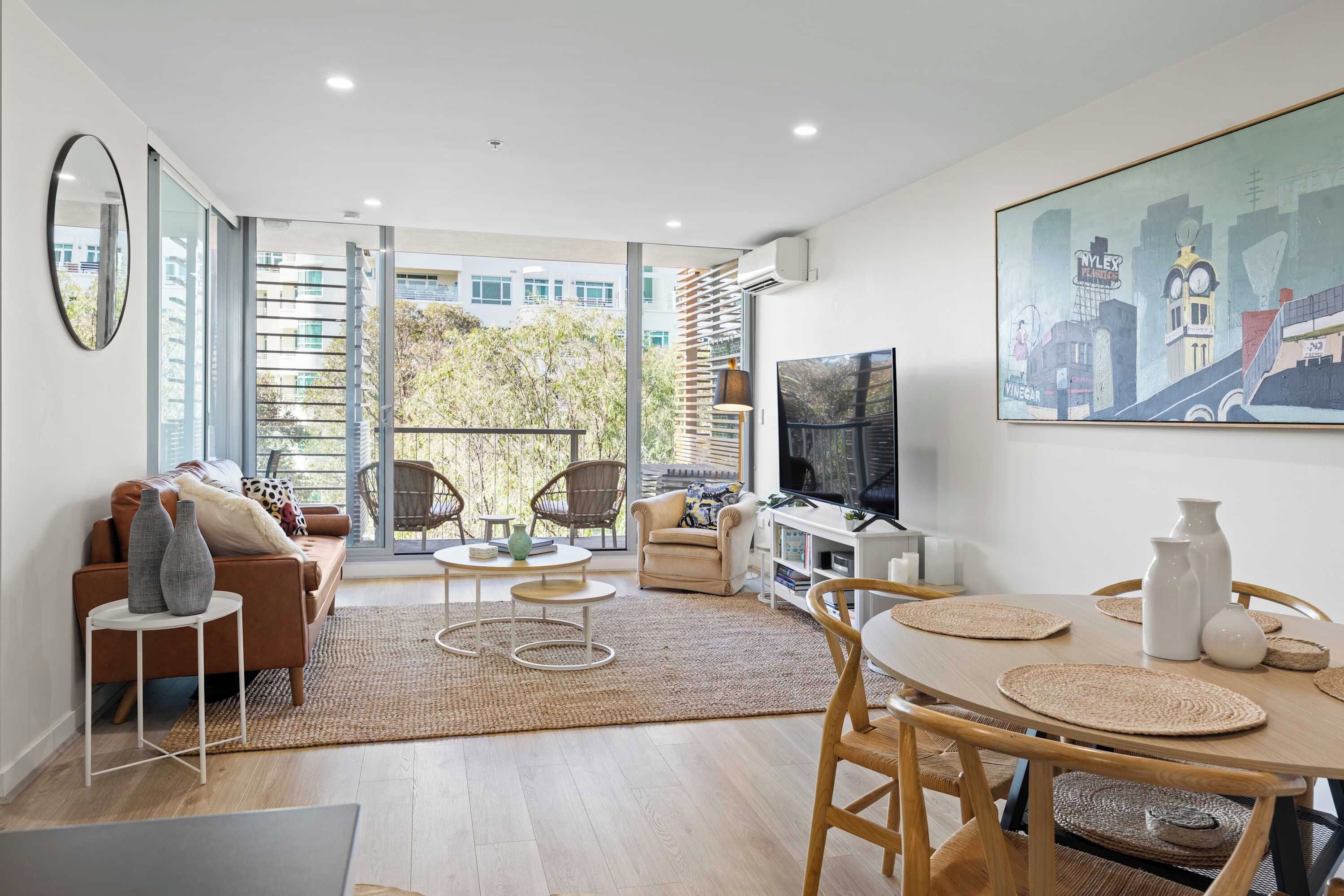 Un salon moderne avec un canapé, des fauteuils, une table à manger et un téléviseur.