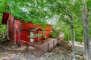 Eine rote Holzhütte mit einer Holzterrasse und einer Treppe zu einem überdachten Bereich.