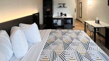 A hotel room with a bed, a desk, a wardrobe, and a kitchenette.