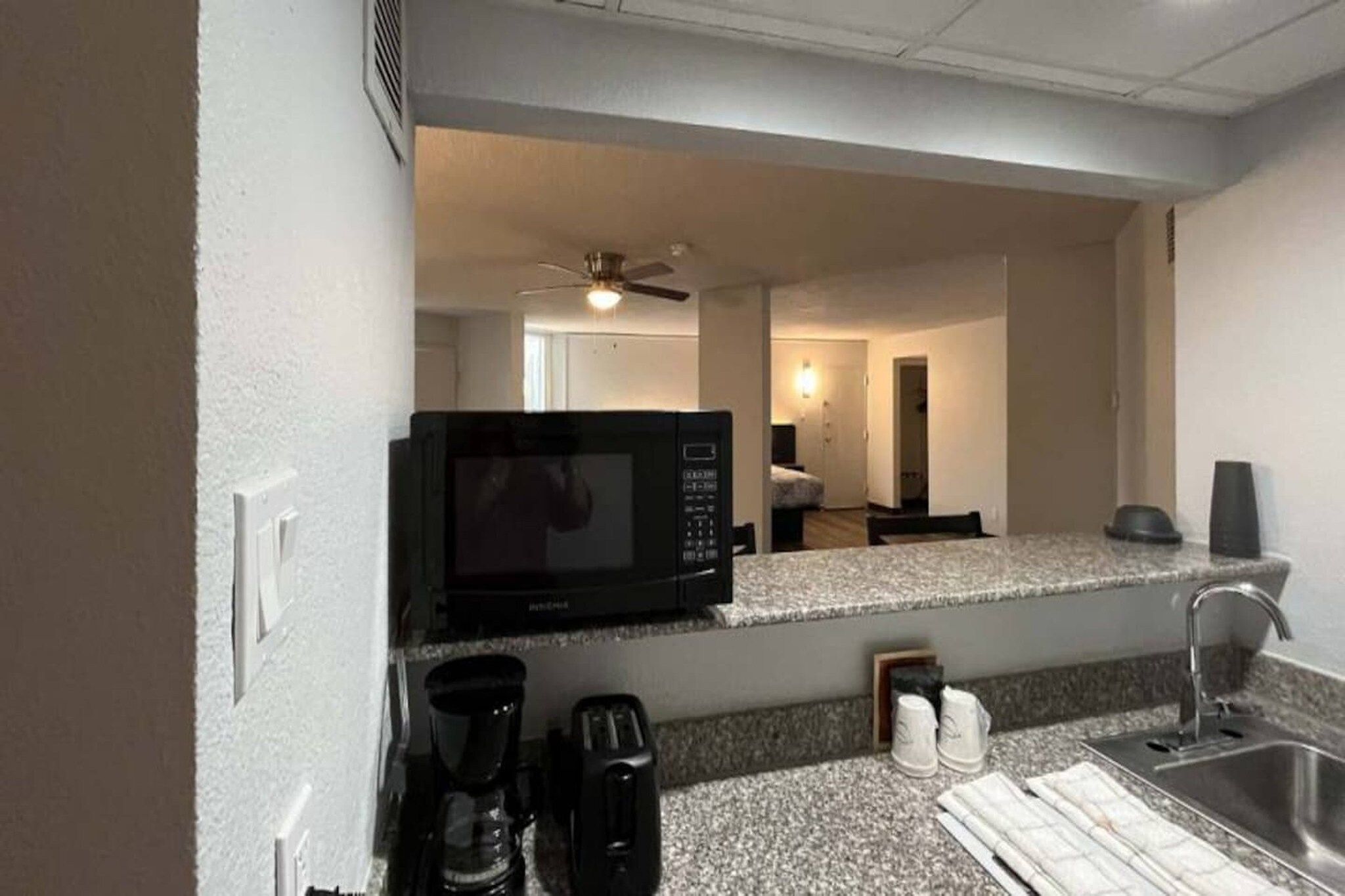 A compact kitchenette with a microwave, coffee maker, and sink.