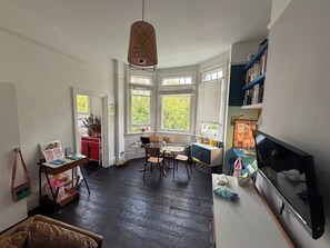 A room with a desk, chairs, a bookshelf, a television, and large windows with blinds. - Characterful 1BDR Flat with Desk in Brixton Hill (London)