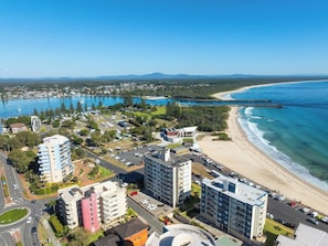 A coastal cityscape with high-rise buildings, a beach, and a marina. - Beachfront Apt w/ Pool & Spectacular Lake Views (Forster)