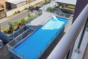 A rooftop swimming pool with a clear view of the surrounding area, including a street and neighboring buildings. - 'Breeze' at The Crest - Spacious & Secure Parking (Forster)