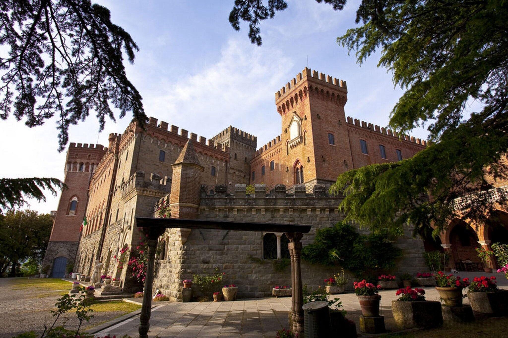A historic castle with multiple towers, a courtyard with potted plants, and a stone bridge.