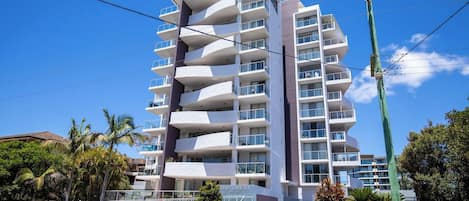 Un hotel de varios pisos con balcones, cielo despejado y palmeras.