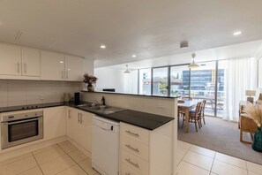 A modern kitchen with white cabinets, a black countertop, and a built-in oven. - Luxury Apartment w/ Pool, Parking, Walk to Beach (Forster)