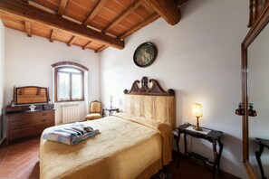 A bedroom with a bed, dresser, and a lamp. - Tuscan Apartment with Garden Views (Poppi)