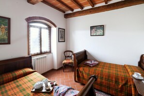 Ein Zimmer mit zwei Betten, einem Sessel, einer Heizung und einem Fenster.