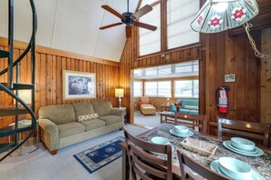 A cozy cabin interior with a wooden interior, a dining area with a table set for four, and a ceiling fan. - Flip Flop Cottage: Lake Access in Clermont (Clermont)