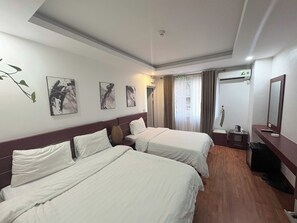 Habitación de hotel con dos camas, una mesita de noche, un espejo y obras de arte en la pared.