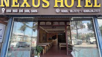 Entrada de un hotel con un letrero que dice 'NEXUS HOTEL' e información de contacto.