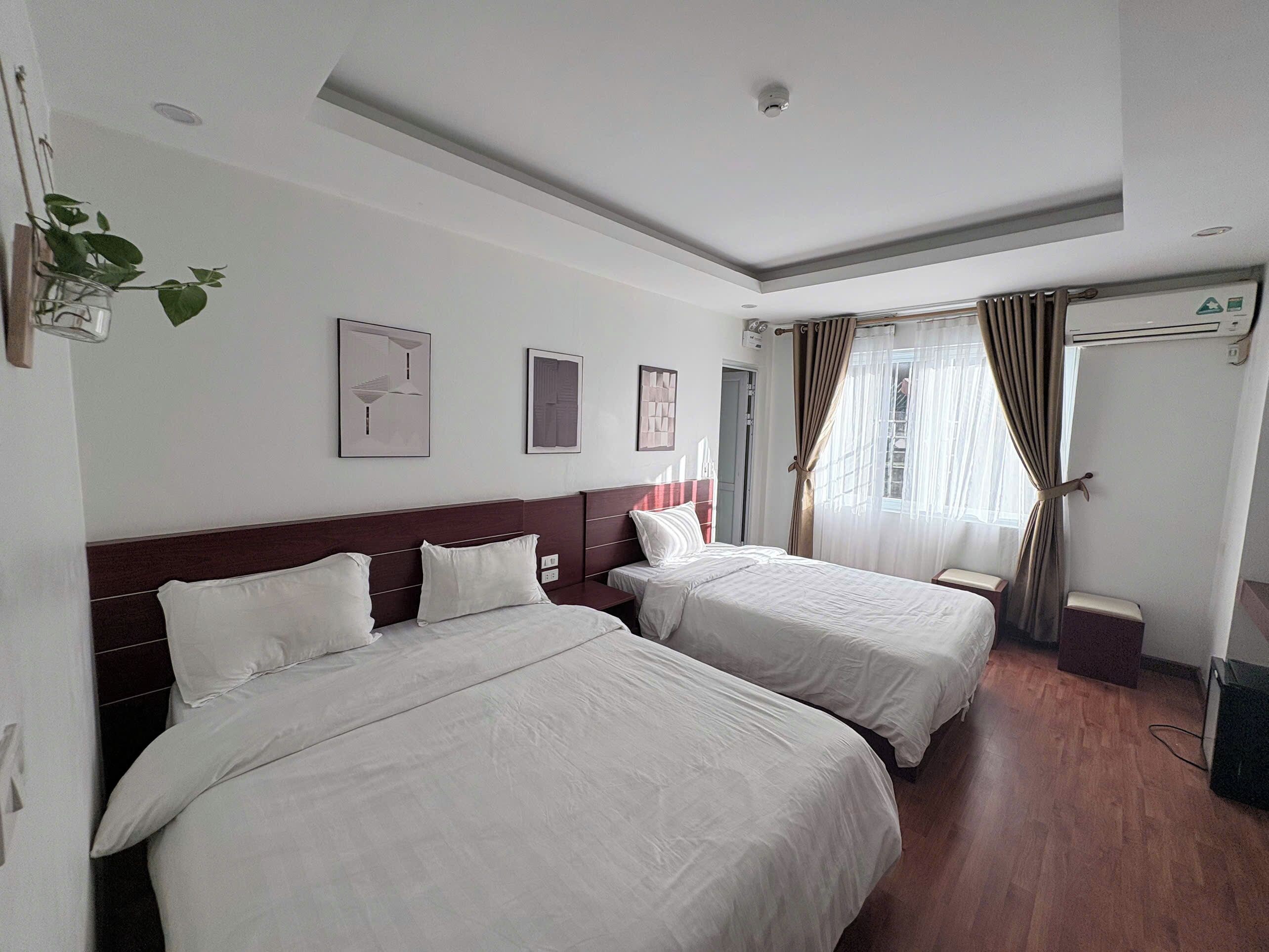 Habitación de hotel con dos camas, un ventilador de techo y una ventana con cortinas.