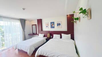 A hotel room with two beds, a large window, and artwork on the wall.