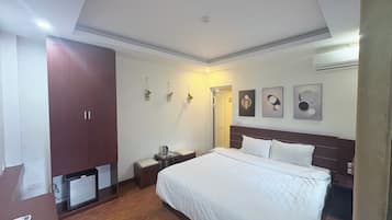 Una habitación de hotel con cama, armario, mesita de noche, escritorio pequeño y televisor.