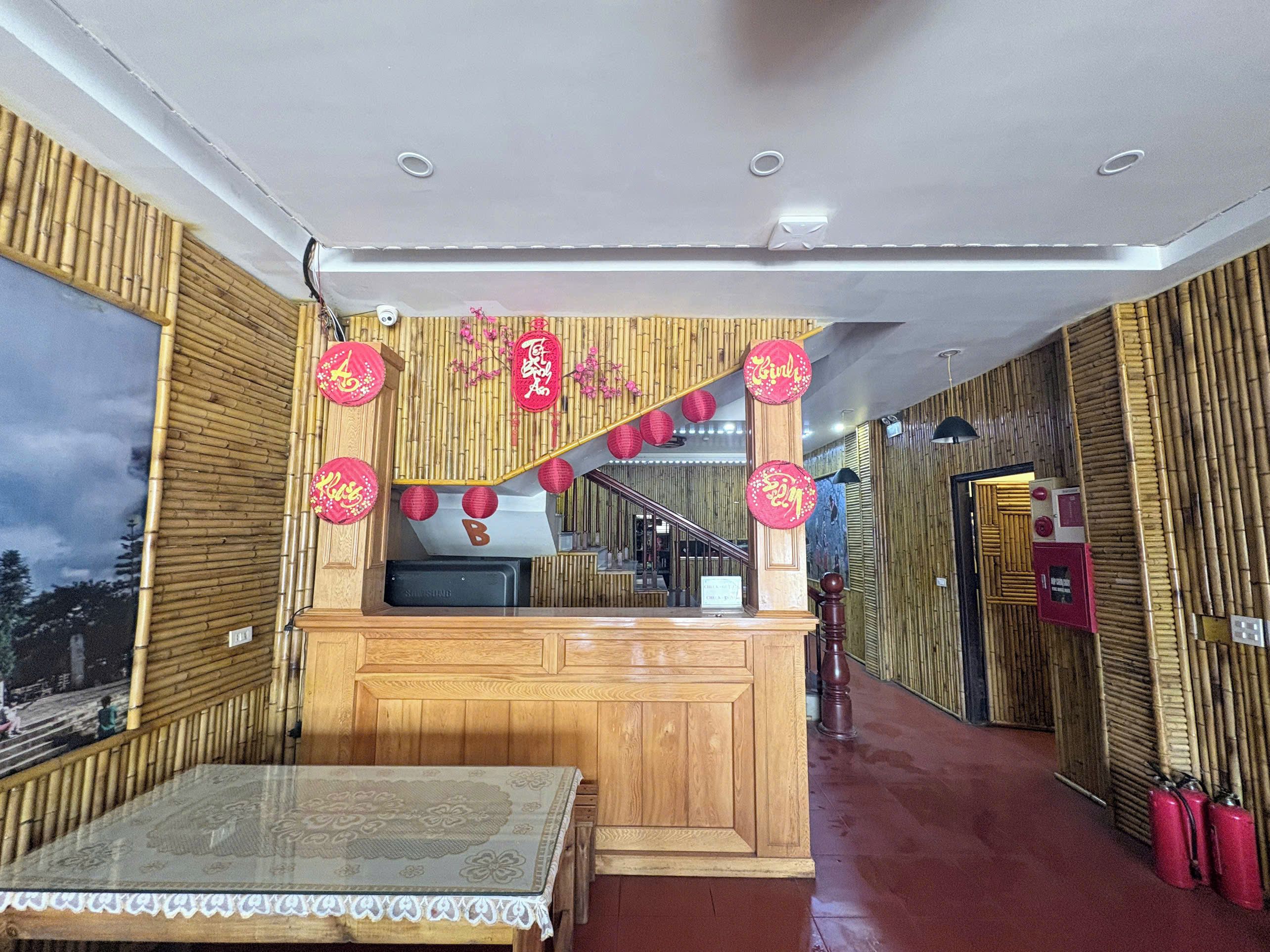 Una habitación de hotel con decoración de madera, una mesa con mantel estampado y faroles rojos.