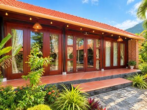 Un hotel con techo de tejas rojas, amplias puertas de cristal y un jardín bien cuidado.
