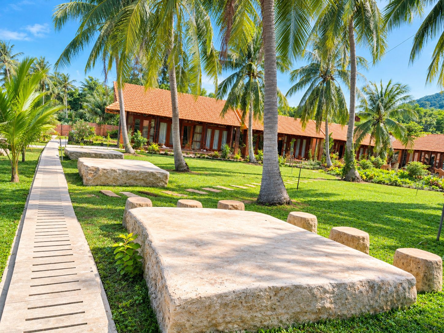 Un resort con un sendero que lleva a un edificio de techo rojo, rodeado de palmeras y vegetación.