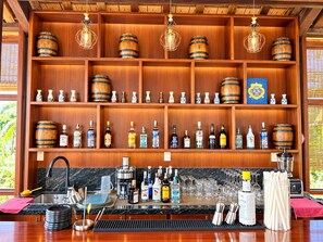 Una zona de bar con estantes de madera, botellas y una máquina de café.