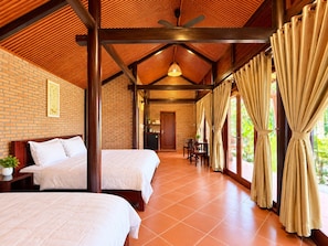 Quarto de hotel com duas camas, área de refeições e cozinha visível através de uma porta aberta.