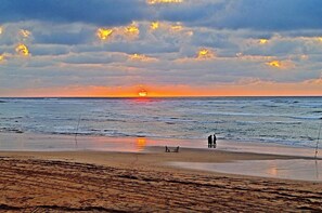 A beach with a sunset, calm sea, and a few people fishing. - 3 Bedrooms Pools Terrace Beach Dar Bouazza (Dar Bouazza)