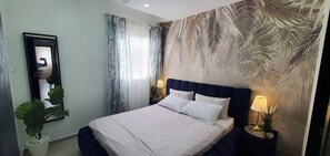 A bedroom with a bed, a mirror, curtains, and a wall with a leaf pattern. - 3 Bedrooms Pools Terrace Beach Dar Bouazza (Dar Bouazza)