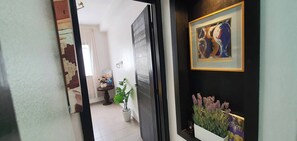 Un couloir avec une porte, un tableau encadré et une plante en pot.