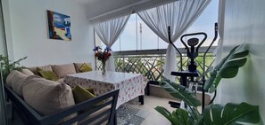 A balcony with a sofa, a table with a floral tablecloth, and a vase of flowers. - 3 Bedrooms Pools Terrace Beach Dar Bouazza (Dar Bouazza)
