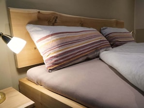A bed with a wooden headboard, two pillows with striped patterns, and a bedside lamp. - Holiday Apartment With 1 Bedroom (Bad Toelz)