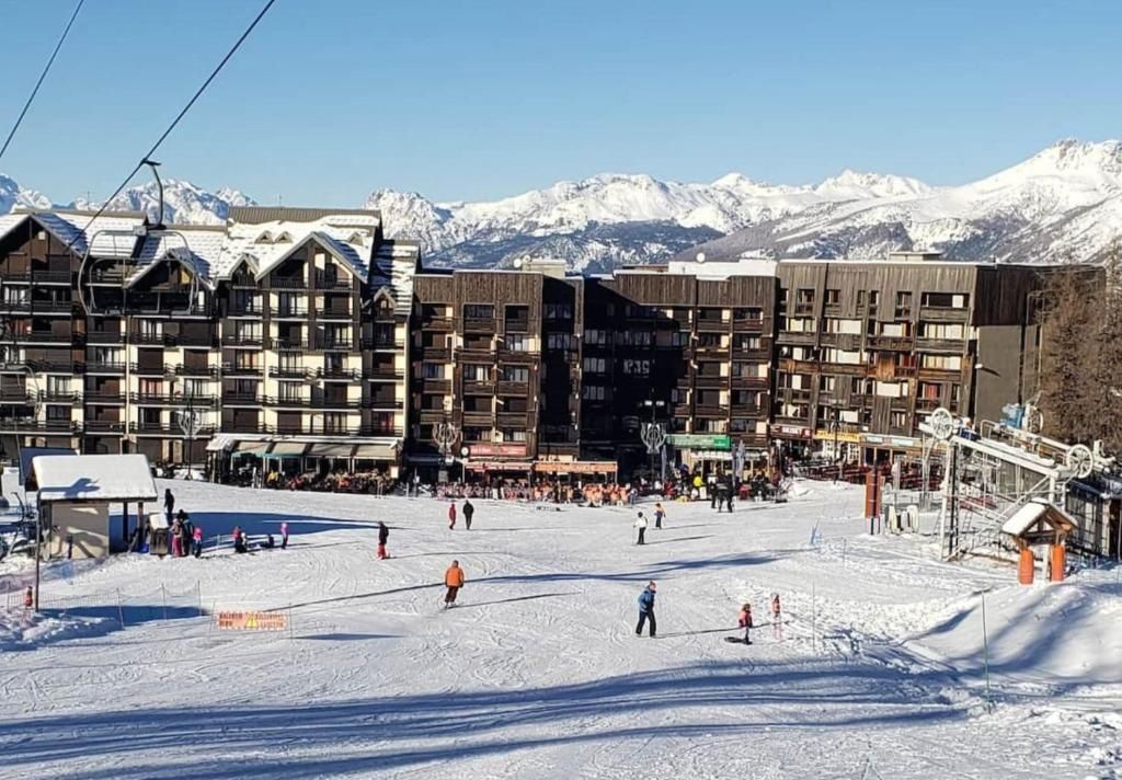 A ski resort with multiple buildings, a ski slope, and a mountainous backdrop.